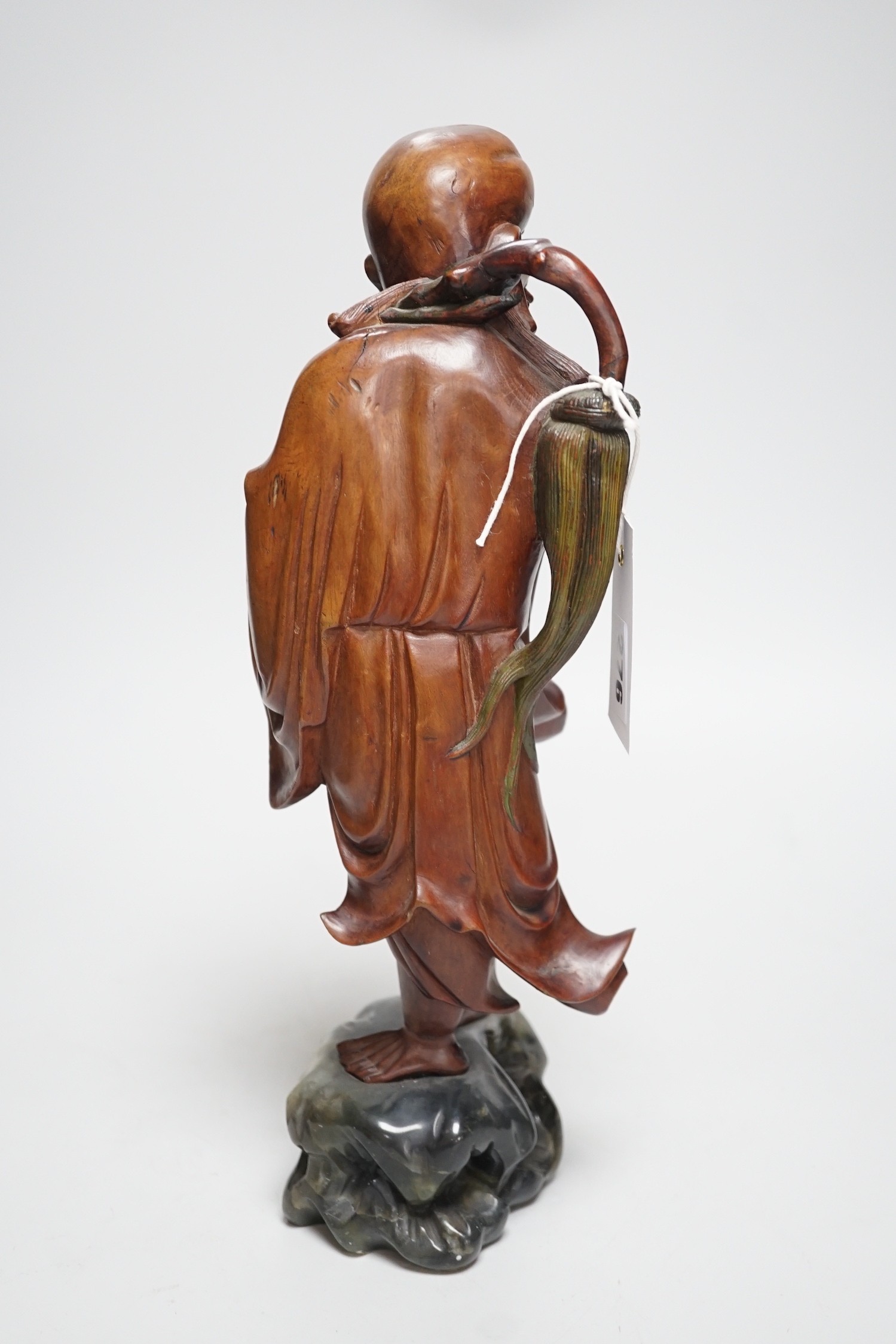 An early 20th century Chinese hardwood carving of a luohan, on soapstone base, 36cm tall